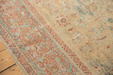 Worn antique Sultanabad rug showing terra cotta meandering leaf border and faded Herati field.
