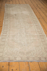 Distressed end of Turkish Oushak runner showing faded beige geometric border and worn fringe.