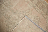 Distressed Oushak rug corner: muted blush, beige pile with even wear, woven foundation, fringe.