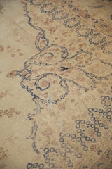 Low-pile texture of a distressed Sparta carpet with scrolling navy arabesques on an antique ivory field.