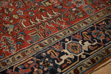 Heriz rug with cherry red field, geometric florals, navy classic turtle border, low pile.