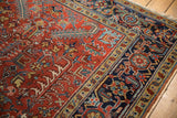 Cherry red geometric floral field and navy turtle design border of this Heriz carpet.