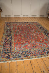 Vintage Heriz rug's navy border with classic turtle design, low pile, and worn cherry red field.
