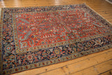 Persian Heriz carpet detail: cherry red field, geometric floral patterns, navy turtle border.