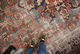 Exposed foundation and worn pile on a vintage Heriz carpet, with brick red and navy motifs.