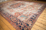 Navy blue samovar turtle and meandering vine border on a brick red vintage Heriz rug.