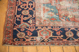 Vintage Heriz carpet corner with navy and brick red borders, visible foundation and knot heads.