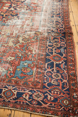 Vintage Heriz rug: navy blue samovar turtle border, and brick red field showing visible foundation.