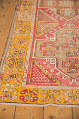 Saffron yellow outer border of the distressed Oushak runner with bright blush geometric patterns.