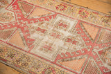 Distressed vintage Oushak rug detail with blush, ivory geometric pattern and visible foundation.