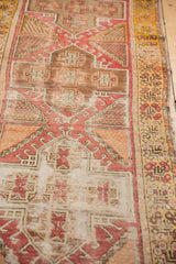 Distressed Turkish Oushak runner with geometric pomegranate medallions in blush, saffron, ivory.