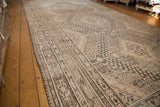 Distressed Khotan carpet showing scalloped field motifs and worn borders in beige and oxidized silver.
