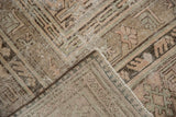 Folded corner of distressed vintage Khotan rug, showing worn pile, visible foundation, muted patterns.