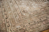 Worn vintage Khotan carpet corner displays faded rose, beige, and soft blue geometric patterns.