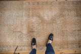 Distressed vintage Oushak runner, faded apricot and beige rams horn motifs, visible foundation.