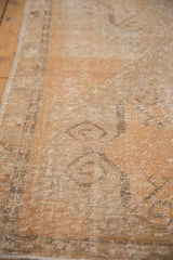 Worn texture of a vintage Oushak runner with apricot and pale charcoal scrolling motifs.
