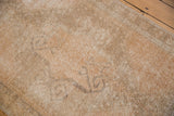 Distressed vintage Oushak rug, faded scrolling rams horn motif in sandy apricot tones with visible foundation.