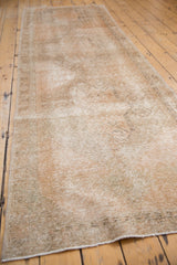 Distressed Oushak runner pile with worn knot heads, visible foundation, and apricot, ivory tones.