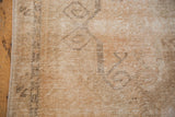 Distressed vintage Oushak rug texture showing even wear, visible foundation, and faded scrolling motifs.