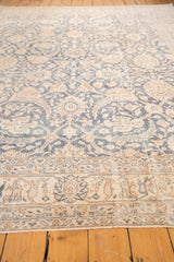 Distressed Turkish Sparta rug shows faded denim blue florals, antique ivory border, even wear.