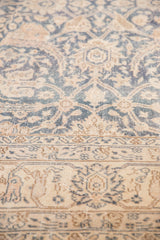 Distressed denim blue and antique ivory floral vinery and border motifs on a vintage Sparta rug.