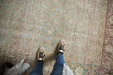 Distressed vintage Tabriz rug with subtle aqua green and cochineal motif, foundation showing.