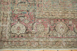 Distressed Tabriz carpet detail: worn cochineal, aqua green motifs, classic border, foundation showing.