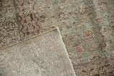 Distressed Tabriz rug corner revealing woven back, worn pile, and aqua green design.