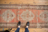 Distressed Oushak runner with abrashed peach field and ivory geometric medallions, showing wear.