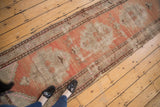 Distressed Oushak runner's abrashed peach, blush, ivory field, geometric motifs, visible wear.
