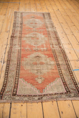 Distressed Oushak runner end, showing abrashed peach field, geometric brown border, wear, and fringe.