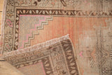 Distressed vintage Oushak rug runner corner showing fringe, hand-knotted back, and worn peach pile.
