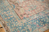 Distressed vintage Tabriz rug corner with blush field and ocean blue floral border.