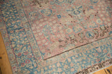 Distressed Tabriz carpet corner showing even wear, blush field with faded pictorial elements and floral ocean blue border.