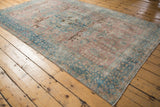 Soft blush and ocean blue tones define a distressed vintage Tabriz carpet with floral motifs, 5'5