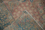 Folded distressed Tabriz rug reveals hand-knotted weave and faded blush, blue pile.