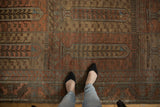 A top-down view showing the distressed texture and multi-paneled design of a vintage Belouch carpet.