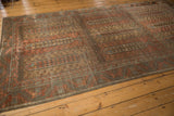 Angled perspective of a vintage Belouch carpet with a distressed, time-softened patina.