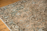 Distressed vintage Baktiari carpet corner with floral vinery, palmettes, and dusty teal on ivory field.