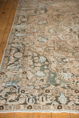 Distressed Baktiari carpet detail with scrolling floral vinery, dusty teal, and visible foundation.