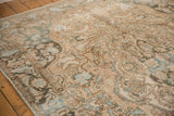 Distressed Baktiari rug with faded ivory, sand, dusty teal, and worn scrolling vinery.