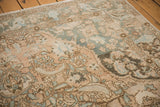 Distressed Baktiari rug corner, showing scrolling vinery, palmettes, ivory, and dusty teal.