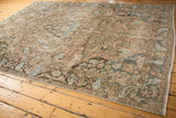 Faded ivory, powder blue, and dusty teal floral vinery on a distressed Baktiari carpet.