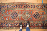 Vintage Heriz runner displays triple medallion, abrash, and localized wear on its red and navy field.