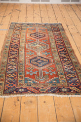 Vintage Heriz runner showing triple geometric medallions, brick red, navy, aqua tones, abrash, and wear.