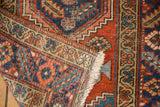 Hand-knotted Heriz rug runner corner with navy, brick red, aqua geometric motifs and fringe.