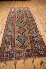Secured hand-knotted fringe and worn red border of an antique Serab runner.