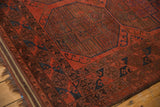 Low pile of vintage Ersari carpet showing geometric guls in cherry red, navy blue, and chestnut brown.