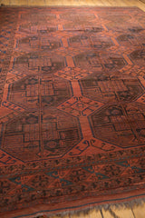 Cherry red field of vintage Ersari carpet with navy blue geometric floral guls and border.