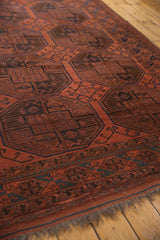 Vintage Ersari rug, cherry red geometric guls in navy, charcoal, and brown, with low pile and fringe.